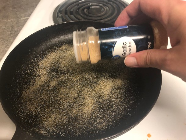 Cooking Eorzea | Adding garlic powder to my cast-iron skillet.
