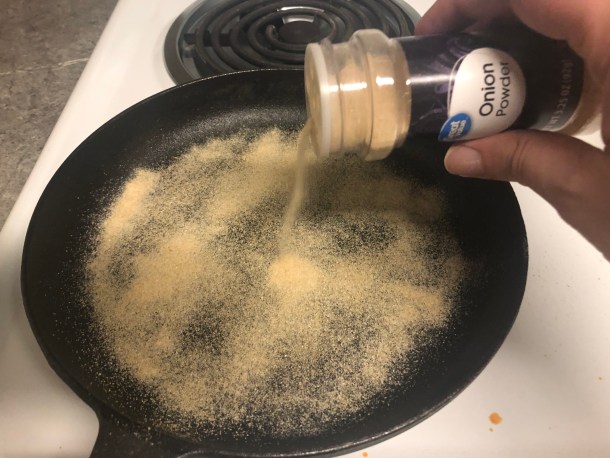 Cooking Eorzea | Adding onion powder to the cast-iron skillet.