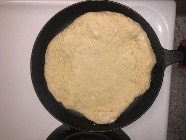 Cooking Eorzea | Adding pizza dough to a cast-iron skillet.